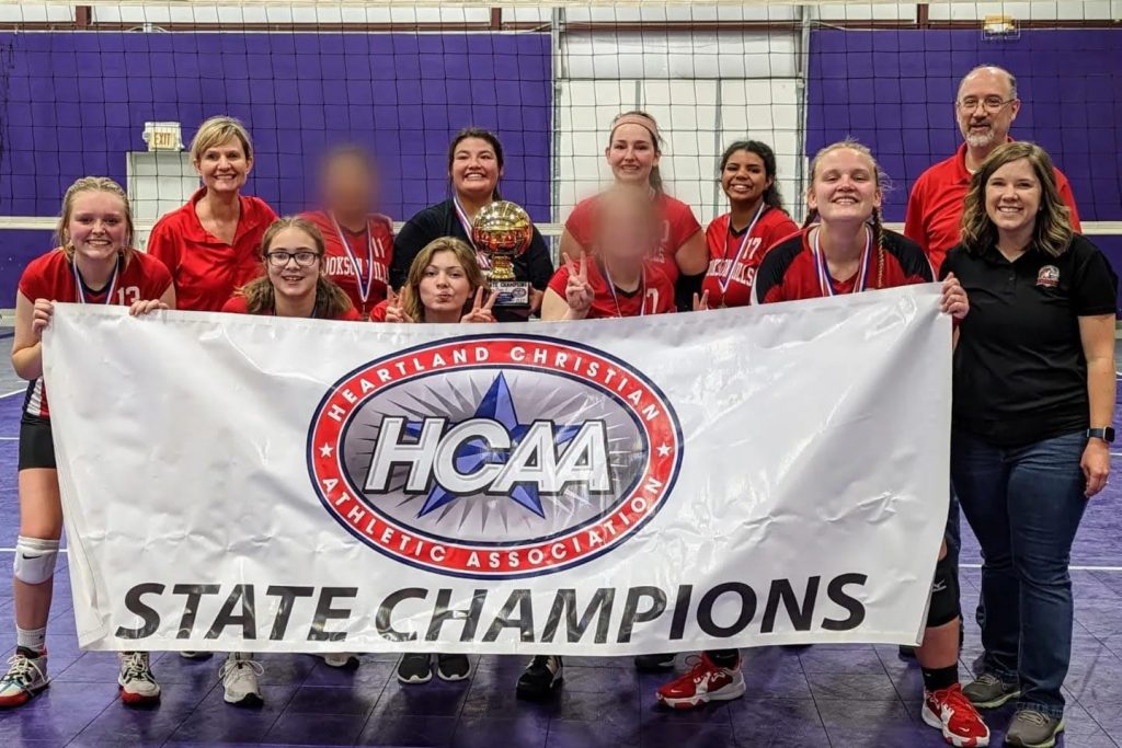 Cookson Hills' Lady Chargers volleyball team and coaches holding an HCAA State Champions banner and gold trophy.