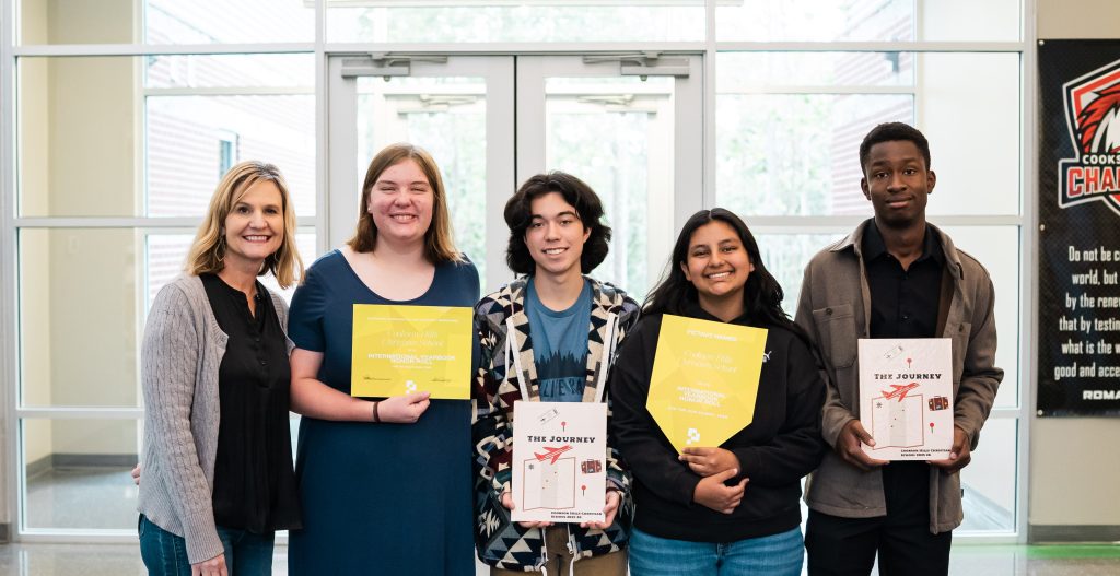 Yearbook teacher April Graney and smiling students holding their award-winning yearbook and Pictavo Honor Roll certificates at Cookson Hills Christian School.
