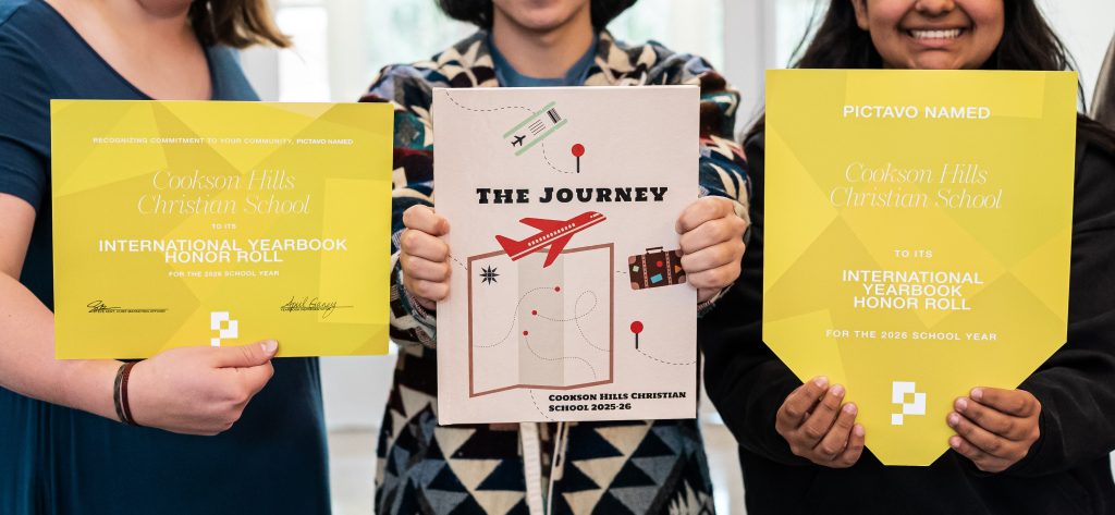 Close-up of the Pictavo International Honor Roll award certificate and the Cookson Hills Christian School yearbook being held by the students.